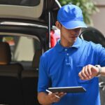 Deliveryman checking time and holding tablet.