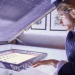 Young man preparing screen on lightbox in traditional print workshop
