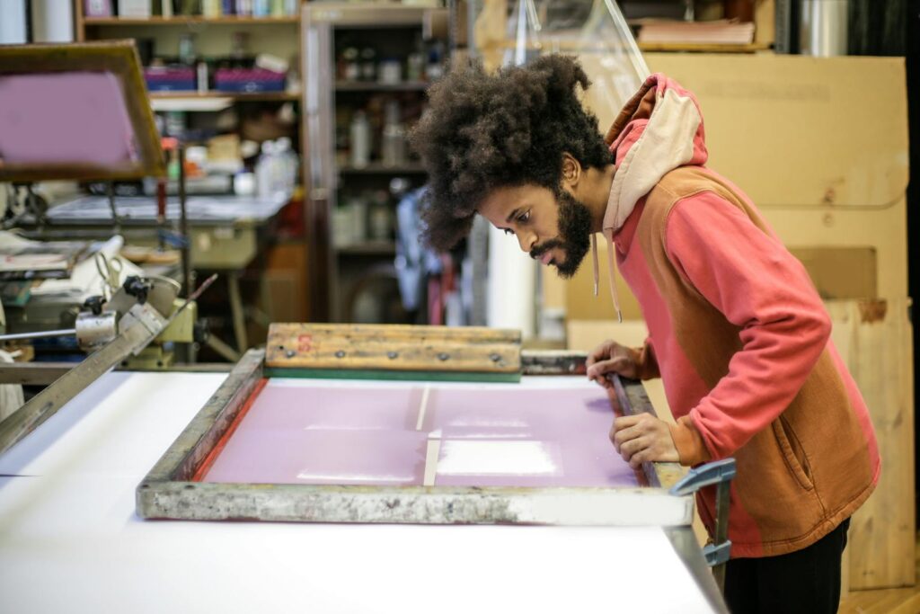 Screen printer pulling a fresh print in a custom apparel workshop