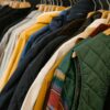 Rack of hanging branded apparel — corduroy jackets and vests in coordinated colors typical of trade show team wear