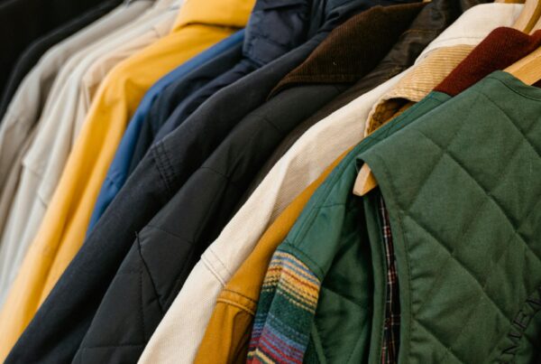 Rack of hanging branded apparel — corduroy jackets and vests in coordinated colors typical of trade show team wear