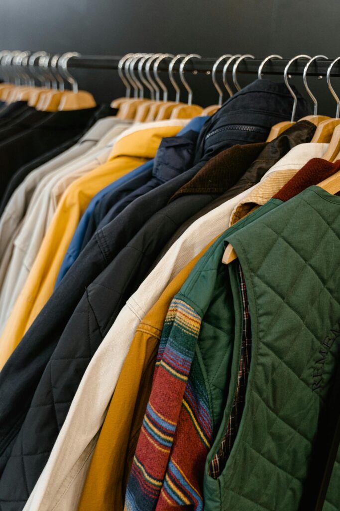 Rack of hanging branded apparel — corduroy jackets and vests in coordinated colors typical of trade show team wear